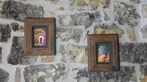 Dos cuadros enmarcados en pared de piedra rústica del Hotel Rural Los Texos en La Riera de Covadonga, con naturaleza muerta decorativa