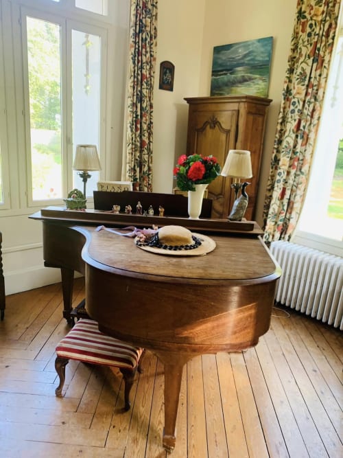Élégant salon du chalet avec grand piano, bureau en bois, cheminée et vues sur le jardin par de grandes fenêtres