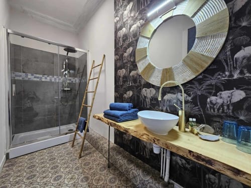 Luxuriöses Badezimmer in der Bastide du Thoré mit begehbarer Dusche, Holzwaschtisch, weißem Keramikwaschbecken, rundem Spiegel und dunklem Elefanten