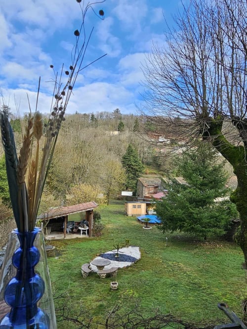 Gartenblick auf Bastide du Thoré mit Steinstrukturen, grünem Rasen und bewaldeten Hügeln in Labastide-Rouairoux