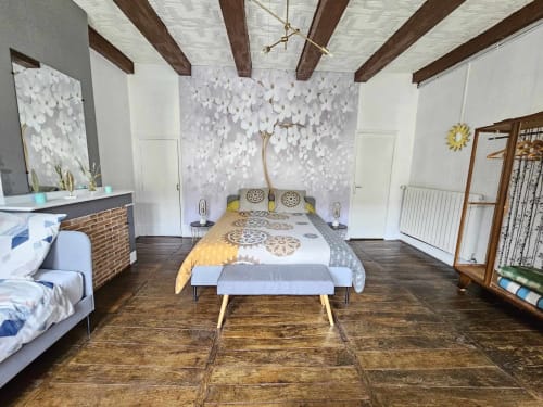 Geräumiges Dreibettzimmer mit freiliegenden Balken, weißer Wandkunst, gelben Akzenten und Gartenblick im Bastide du Thoré B&B