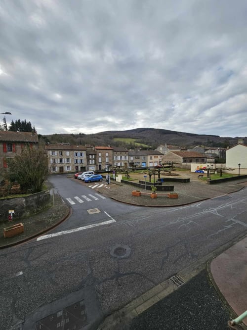 Place de Labastide-Rouairoux avec bâtiments historiques, jardin central et vue sur les montagnes à la Bastide du Thoré