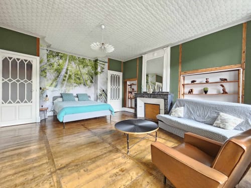 Spacieuse chambre de la Bastide du Thoré avec lit turquoise, murs verts, cheminée et mobilier contemporain