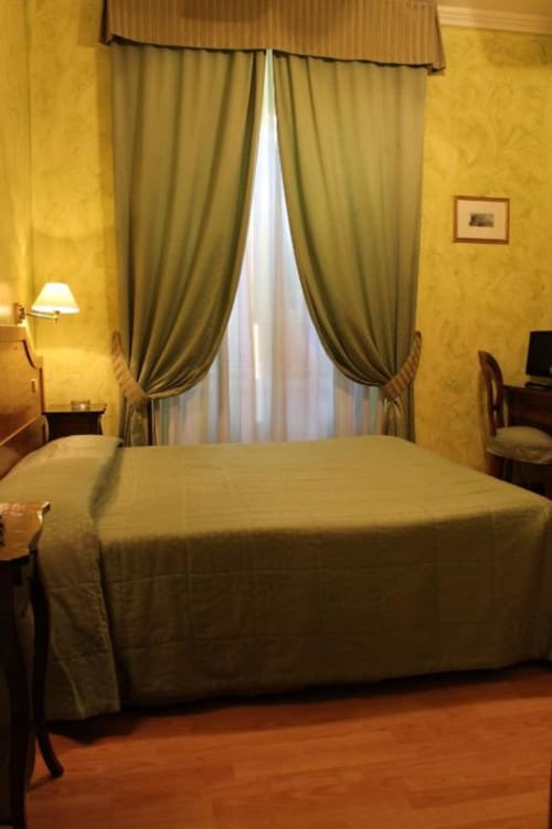 Elegante camera doppia presso l'Hotel Fiori Rome con letti gemelli, pareti dorate, tende verdi e pavimento in parquet