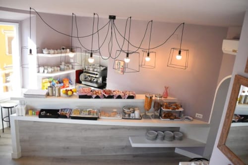 Hotel Fiori Roma café counter with espresso machine, pastries, and modern geometric pendant lighting