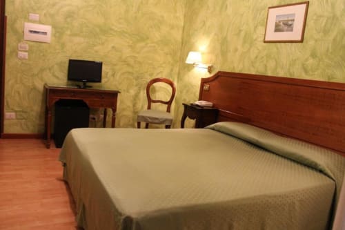 Camera doppia Hotel Fiori a Roma con letto in legno, scrivania con TV, carta da parati decorata e pavimento in parquet