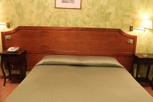 Elegante camera d'hotel presso l'Hotel Fiori Rome con testata in legno, letti gemelli, comodini con lampade e tonalità beige