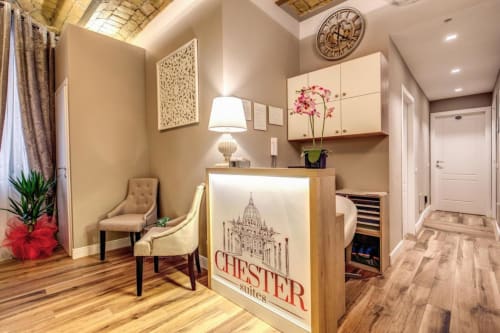 Area reception del Chester Suites Roma con sedute beige, scrivania in legno e eleganti arredi