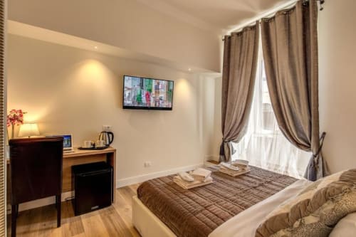 Elegante camera doppia presso Chester Suites Rome con TV a parete, scrivania, tende da terra a soffitto e illuminazione calda