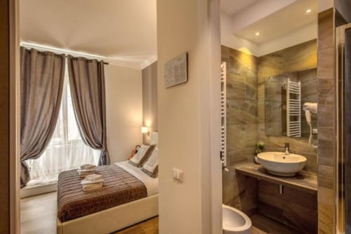 Camera doppia Chester Suites Roma con bagno ensuite, doccia in marmo, lavabo a bacinella e finestra con tende