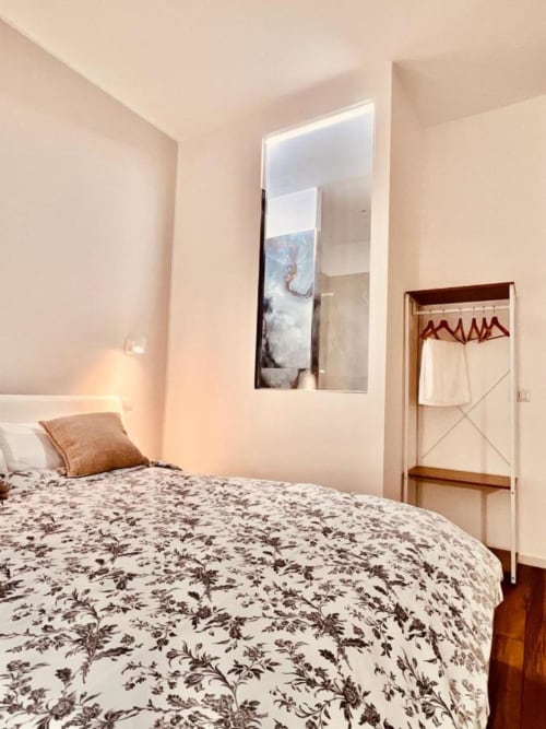 Camera accogliente presso Finella Charming Rooms a Bari con biancheria floreale, dettagli in legno e bagno moderno