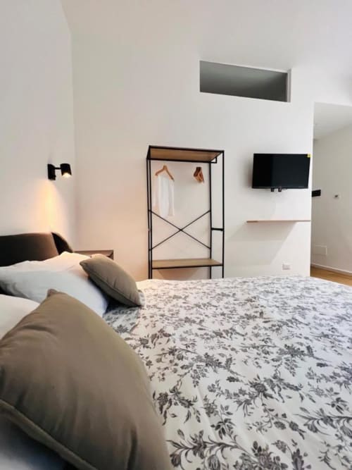 Camera moderna presso le Finella Charming Rooms a Bari con letto, attaccapanni, TV e design minimalista bianco