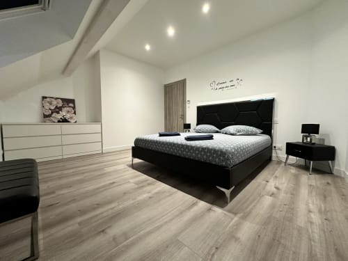Chambre moderne aux Gîtes Les Camélias 71 à Oslon avec lit noir, commode blanche et parquet
