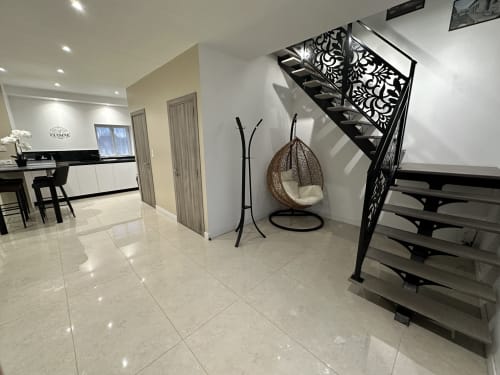 Entrée contemporaine des Gîtes Les Camélias avec escalier design, fauteuil suspendu et cuisinette ouverte