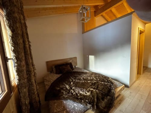 Chambre du chalet Les Louettes à Saxon avec poutres en bois, lit à literie motifs et lumière naturelle