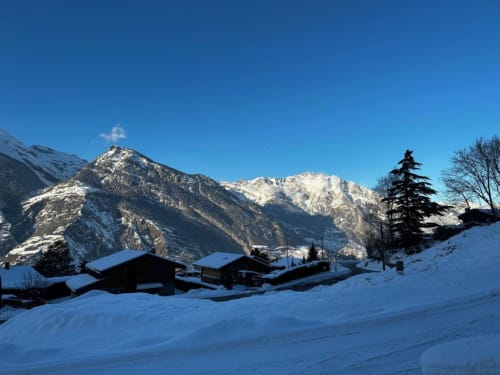 Chalet d'hôtes Les Louettes à Saxon avec montagnes enneigées et pics alpins sous ciel bleu dégagé