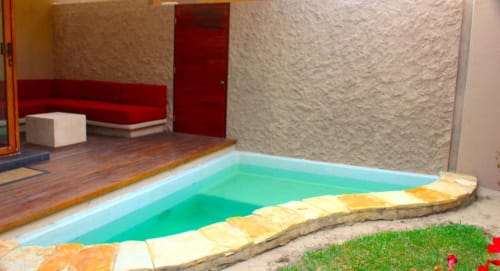 Gartenzimmer des Isla Tajín Beach & River Resort mit türkisfarbenem Pool, rotem modernem Mobiliar und üppiger Landschaftsgestaltung in Tuxpan