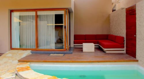 Zimmer des Isla Tajín Beach & River Resort mit türkisblauem Pool, rotem Sofa, Holzterrasse und Gartenblick in Tuxpan, Mexiko