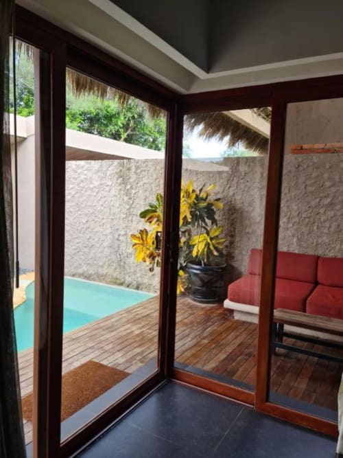 Modernes Zimmer im Isla Tajín Beach Resort in Tuxpan mit Glastüren zur Poolterrasse, roten Sitzmöbeln und Gartenblick