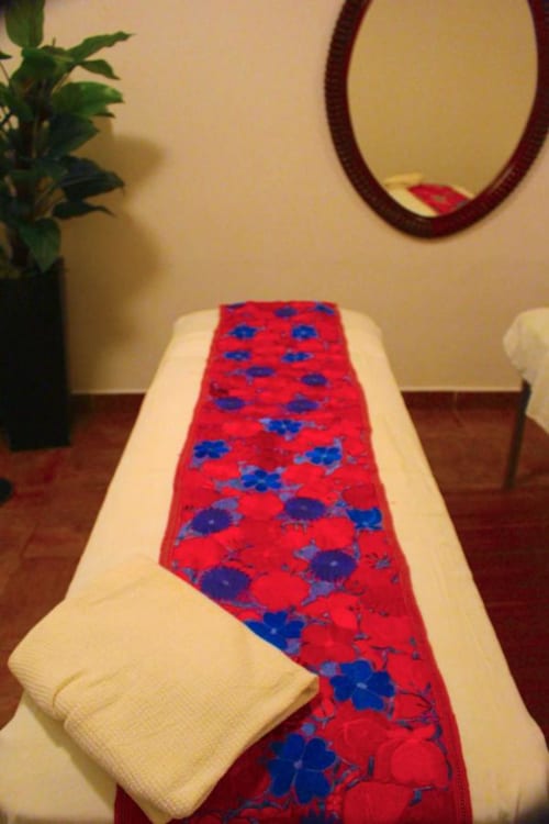 Roter und blauer Blumenlaufer auf weißem Bett im Isla Tajín Beach & River Resort in Tuxpan, Mexiko
