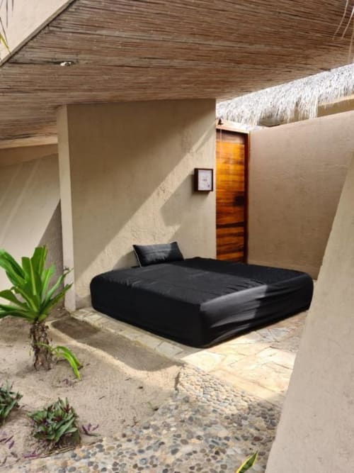 Schwarzes Bett im Gartenzimmer des Isla Tajín Beach & River Resort in Tuxpan, Mexiko, mit Strohdach und tropischen Pflanzen