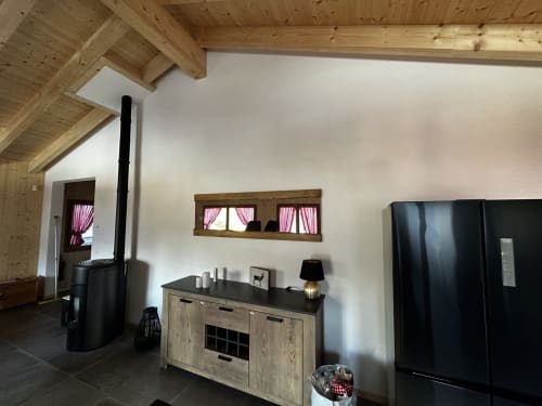 Salon moderne du Chalet d'hôtes Les Louettes à Saxon avec poutres apparentes, cheminée et vue sur les montagnes