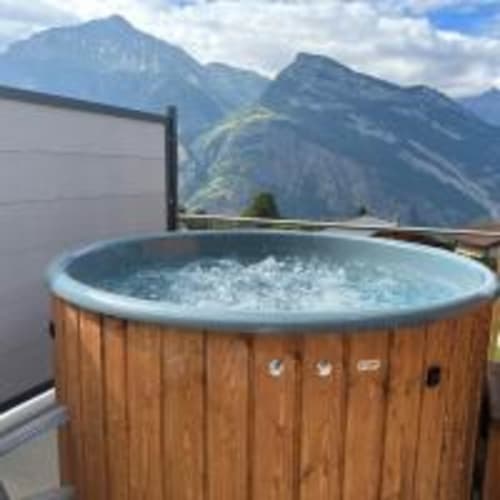 Bain à remous en bois avec eau fumante surplombant les Alpes suisses au chalet Les Louettes à Saxon