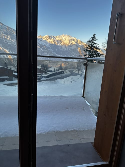 Vue enneigée depuis le balcon du chalet Les Louettes à Saxon, Suisse valaisanne, avec les pics alpins au lever du soleil