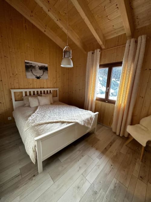 Chambre douillette du chalet Les Louettes avec lit blanc, poutres apparentes, vue sur les montagnes, Saxon
