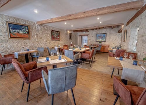 Comedor elegante con muros de piedra, vigas de madera y asientos variados en Domaine de Bize Mirepoix en Ariège