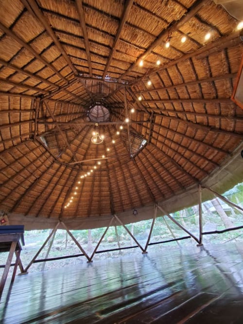 Techo de madera con techo de paja e iluminación cálida en el hostal Cayuco Maya de Bacalar, México