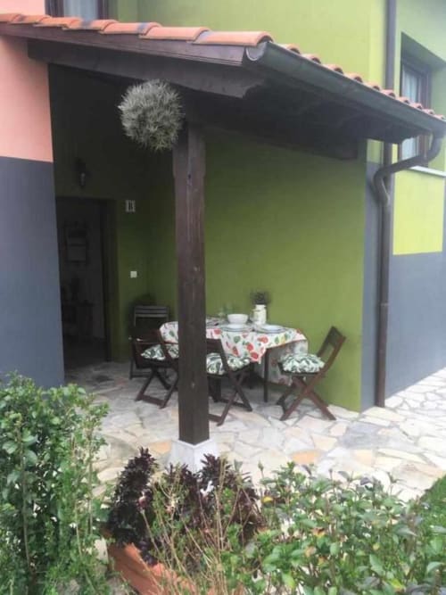 Cozy patio at Esto si es vida hotel in Ribadesella with dining area, green walls, and terracotta roof