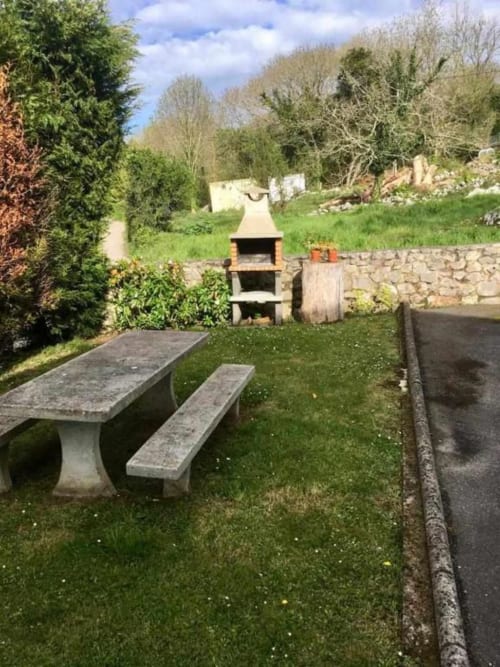 Garden seating area with stone picnic table at Esto si es vida hotel in Ribadesella, Spain