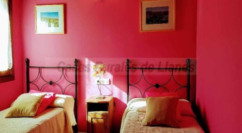 Dormitorio rosa brillante con dos camas individuales de marco metálico negro, en el hotel Esto si es vida en Ribadesella, España