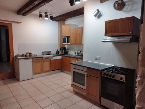 Amplia cocina en L'étape Du Fanfoué BnB en Chamrousse con muebles de madera, electrodomésticos de acero inoxidable y vigas de madera