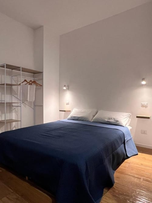 Camera moderna a Finella Charming Rooms a Bari con biancheria blu navy, pareti bianche, pavimento in legno e arredamento minimalista