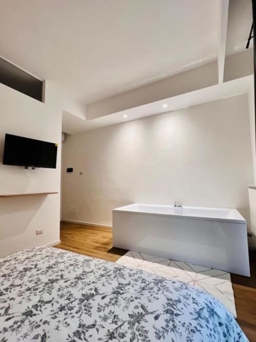 Camera moderna di Finella Charming Rooms a Bari con biancheria floreale, vasca bianca, TV a parete e design minimalista