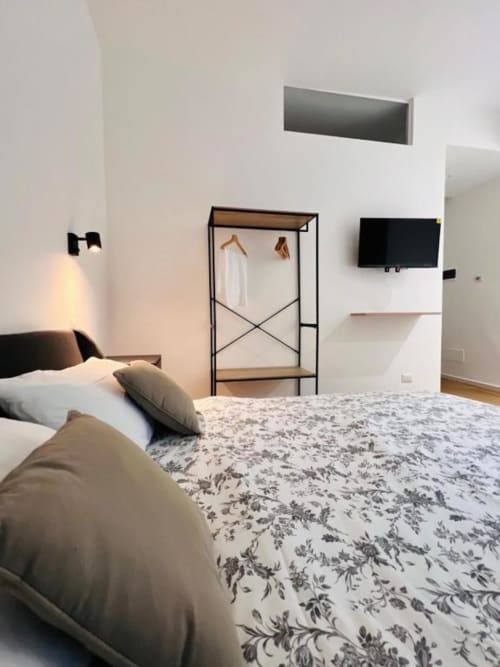 Camera moderna a Finella Charming Rooms a Bari con letto, armadio minimalista, TV e vista sulla città
