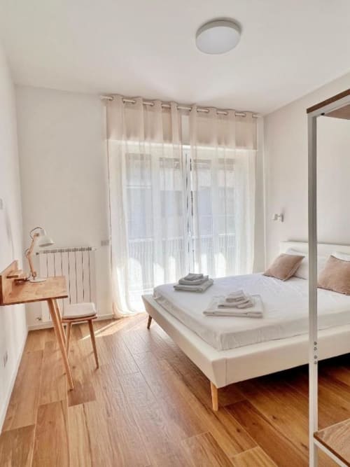 Camera moderna presso Finella Charming Rooms a Bari con letto a baldacchino, scrivania in legno e vista sulla città dal balcone