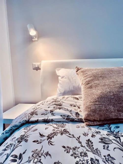 Camera accogliente presso Finella Charming Rooms a Bari con biancheria floreale, cuscini e luce per la lettura