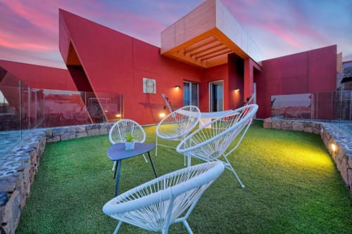 Villa roja moderna con sillas blancas de alambre en terraza verde al atardecer, Villa Cacemar, Maspalomas