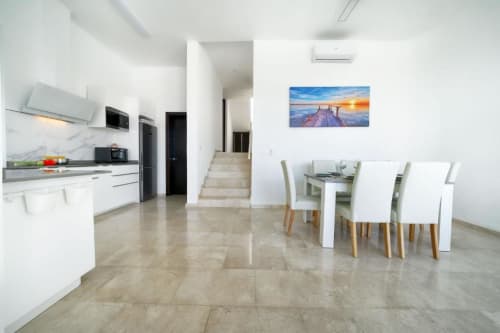 Cocina y comedor moderno en Maspalomas con muebles blancos, suelo de mármol y vistas al mar