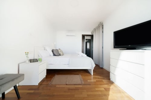 Dormitorio moderno en Villa Cacemar en Maspalomas con suelo de madera, cama blanca, TV y vistas a la piscina