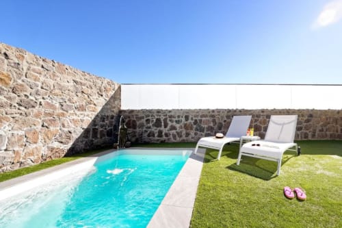 Piscina privada Villa Cacemar con agua turquesa, tumbonas y muros de piedra en Maspalomas