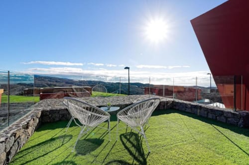 Dos sillas blancas de alambre sobre césped verde con vistas a las montañas en Villa Cacemar en Maspalomas