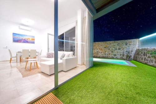 Villa Cacemar en Maspalomas: elegante vivienda moderna con piscina privada, césped verde, muros de piedra y cielo estrellado