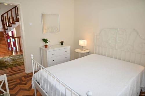 Chambre lumineuse et spacieuse à la Villa Sor avec lit en métal, commode, table de nuit et parquet