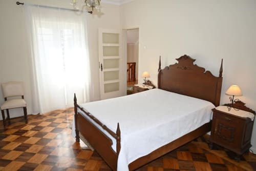 Chambre élégante à la Villa Sor avec lit à baldaquin en bois, draps blancs et mobilier traditionnel à Ponte de Sor, Portugal