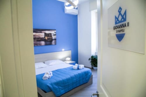Camera moderna blu e bianca a Borgo Angioino BnB a Napoli con branding Giovanna II visibile