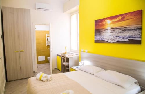 Camera giallo brillante al Borgo Angioino B&B a Napoli con letti matrimoniali, artwork tramonto al mare e comfort moderni